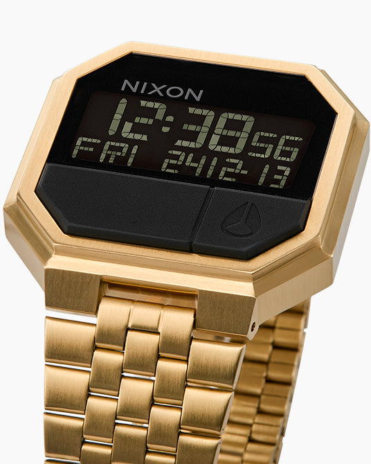 Gold Nixon digital watch with black display on a white background