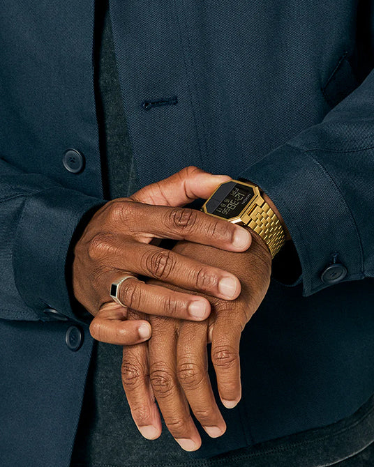 Person wearing a gold watch with a dark jacket