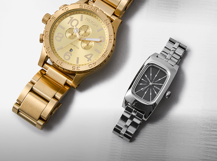 Gold and silver watches on a reflective surface